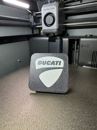 Tapa decorativa con logo Ducati impresa en 3D para el soporte antirrobo