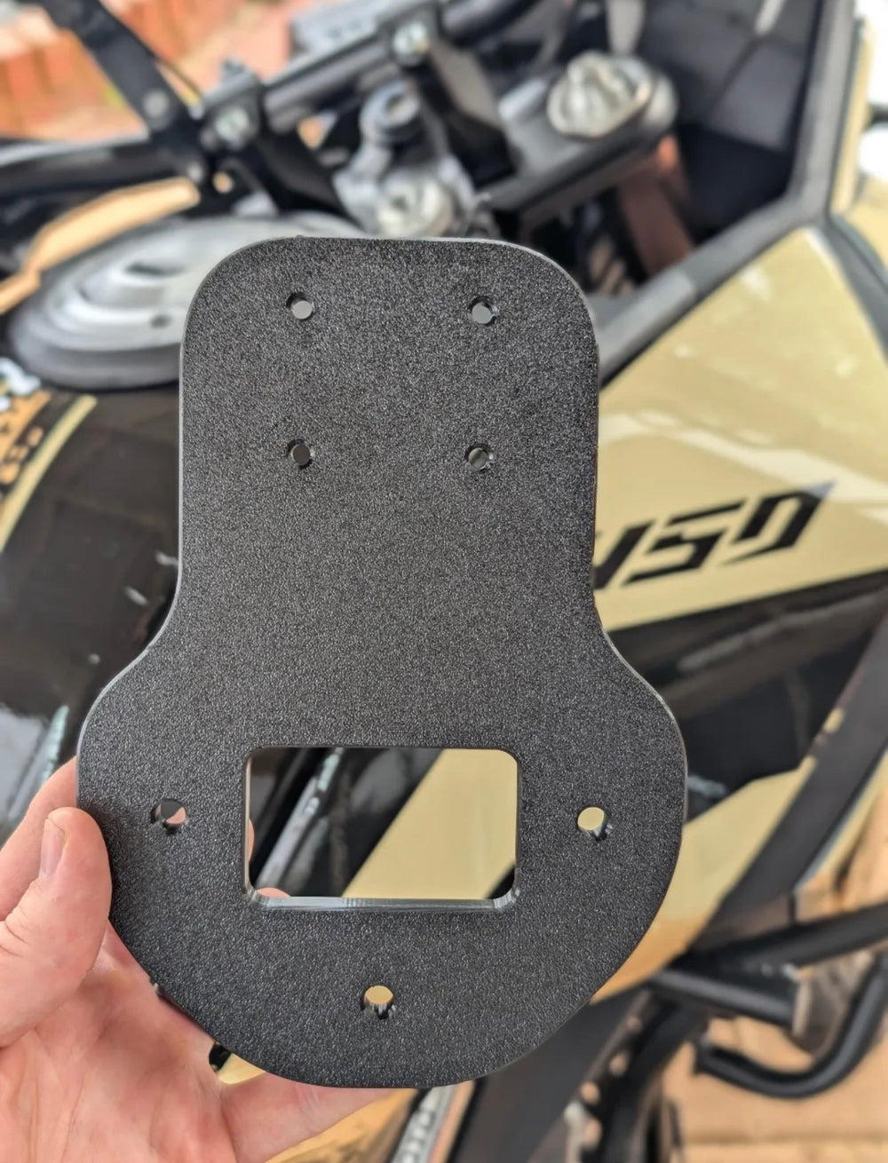 Adaptador Quad Lock para CFMoto 450MT sujeto en la mano junto a la moto